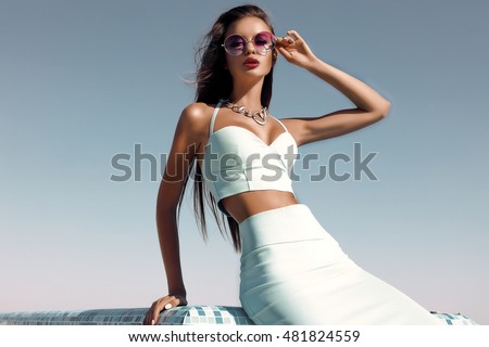 Outdoor fashion lifestyle portrait,beautiful dark hair woman with perfect long fluffy  hairs,wearing stylish elegant clothes.Mint costume,work outfit,Autumn style.,posing over blue sky,round glasses