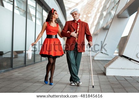 Old man saunters with a young girl under the handle. Royalty-Free Stock Photo #481845616