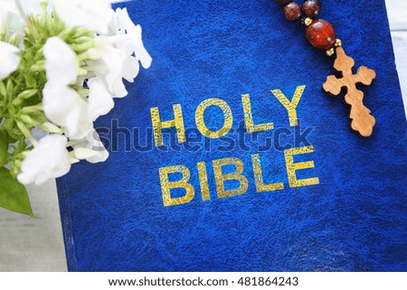 Wooden cross with flowers and Bible, top view