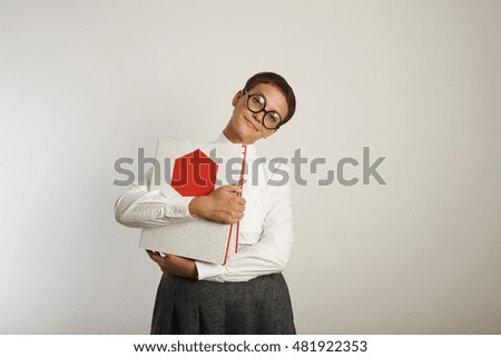 Young female teacher in old-fashioned clothes holding red and white binders and looking expectantly into the camera against white background