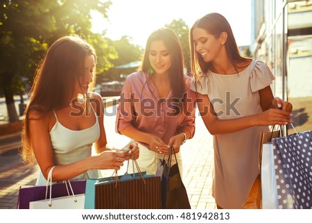 Beautiful girl with packages after shopping A picture of a group of happy friends shopping in the city.  Girl walking around the city after shopping. good mood. Evening light. shopping concept