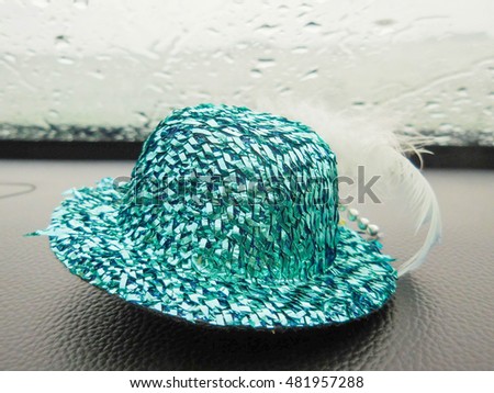 So blue little hat put on a car console with the sea view in a rainy day
