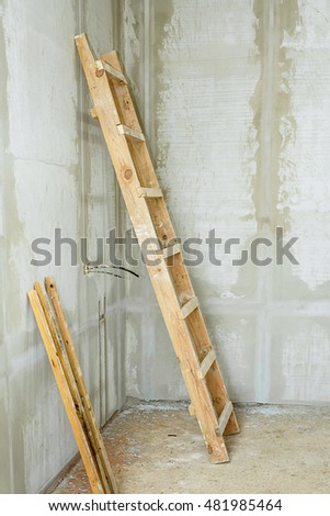 Ladder on concrete wall, construction site, wooden step ladder on work place,
