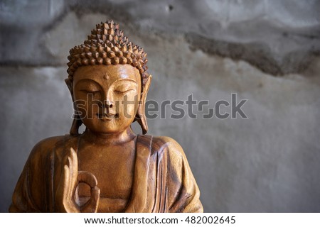 Wooden buddha statue, on grey cement background