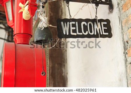 vintage and retro welcome sign with bell, holy thread, red box and lamp at pub or restaurant on street