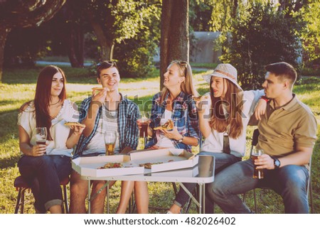 Cheerful friends on picnic in the park. Smiling and talking
