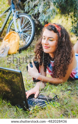the girl has arrived by bicycle to park, has sat down under a tree to have rest. in hands a  camera roll