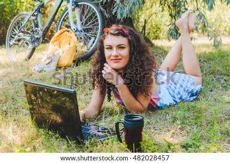 the girl has arrived by bicycle to park, has sat down under a tree to have rest. in hands a  camera roll