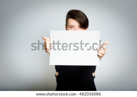 short-haired girl is hiding behind a white banner, close-up, isolated on a gray background