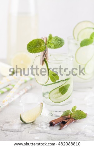 Cold detox cocktail with cucumbers, lime, mint and cinnamon with ice in the glass on the table