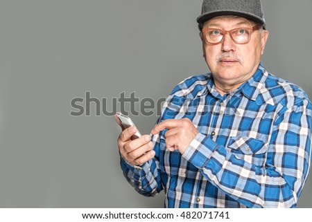 Old cute man wearing glasses using mobile phone isolated on grey background