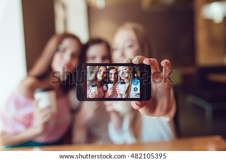 Three young girls are doing selfie in fast food restaurant