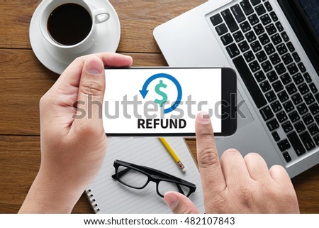 REFUND and Tax Refund Fine Duty Taxation  message on hand holding to touch a phone, top view, table computer coffee and book Royalty-Free Stock Photo #482107843