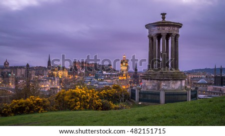 Edinburgh, Scotland cityscape at night, view from the Calton Hill, with Edinburgh castle in the background and Dugald Stewart Monument silhouette in the front. Artistic selective color edit.