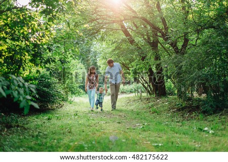 Young happy family of three walking in the park. Happy parenting. Father and mother with son. Royalty-Free Stock Photo #482175622
