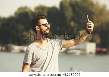 Handsome young man with beard taking selfie outdoor