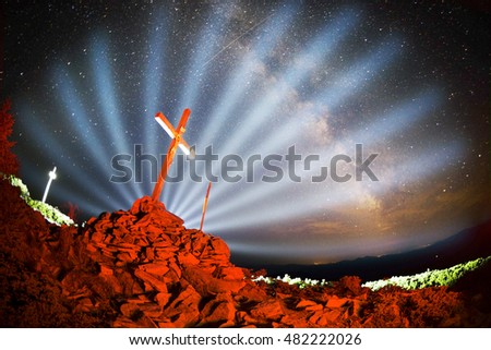 Cross on Mount Strymba wooden raised to the glory of God, Jesus Christ. Night light lighting a fire on a background of mountains alpine vegetation stones under the stars of the Milky Way