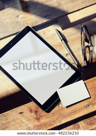 Closeup Modern Tablet Blank White Screen,Glasses Wood Table Inside Interior Coworking Loft.Empty Mockup Design Clear Paper Business Card Corporate Message Background.Mock Up Private Objects Text
