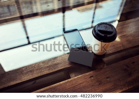 One Blank Black Business Card Mockup Wood Table.Take Away Coffee Cup Coworking Studio Place.Modern Phone Work Office Reflection Glass Background.Mock Up Objects Ready Private Message.Horizontal Photo