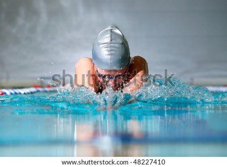 woman swims using the breaststroke in indoor pool Royalty-Free Stock Photo #48227410