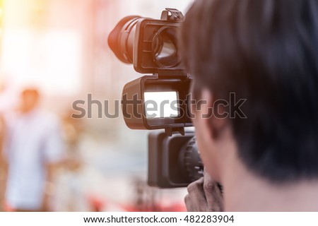 Videographer takes video camera whit white screen and blur image of group people in the background with free copy space for your text