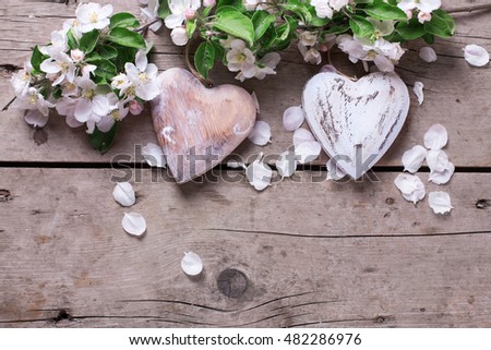 Two decorative hearts and apple tree flowers  on vintage wooden background. Selective focus. Place for text.
