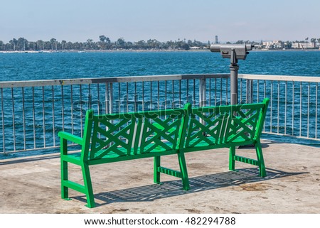 Park bench on the pier at the Cesar Chavez Park in San Diego, California, with Coronado and the San Diego bay in the background.