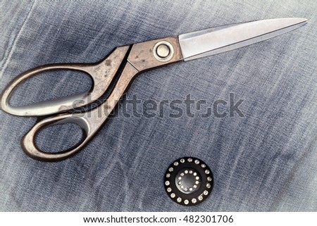 Black buttons with rhinestones and tailoring scissors on denim