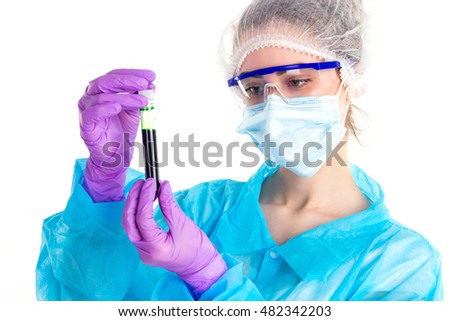 On a white background the woman in a blue protective coat with gloves is looking on a tube with a black liquid.