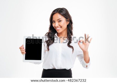 Cheerful young asian businesswoman holding tablet with blank screen and showing okay gesture over white background