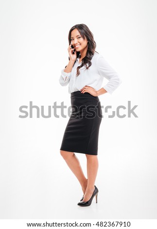 Full length portrait of a smiling asian businesswoman talking on the phone isolated on a white background