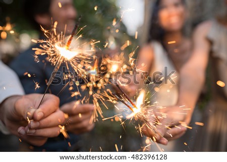 Hands of people holding glowing bengal lights Royalty-Free Stock Photo #482396128