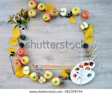 Autumn frame from fruits, leaves and cones and palette with paints on wooden ,nature background with copy place for text or logo
