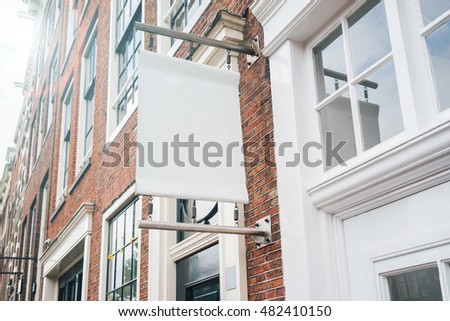 Photo blank signboard on the city street. White square signboard on the brick wall. Mock up.