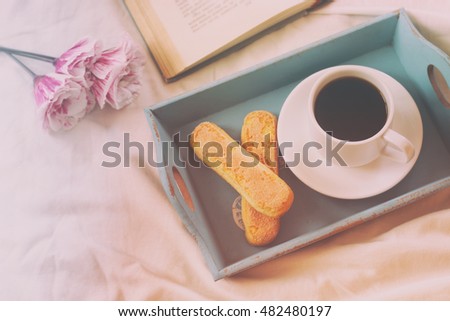 Romantic breakfast in the bed: cookies, hot coffee, flowers and open book. vintage style image , photographed without editing software, using handmade filter