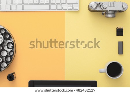 Work space on yellow table of a creative designer or photographer with laptop, tablet, cameras other objects of inspiration, copy space. Home studio concept of technology trends. View from above.