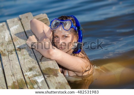 girl with an underwater mask and snorkel near the old pier. Young happy beautiful summer diving woman with swimming mask and snorkel preparing to dive