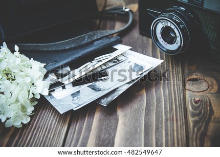 Vintage photo camera with stack of photo shots on wooden background