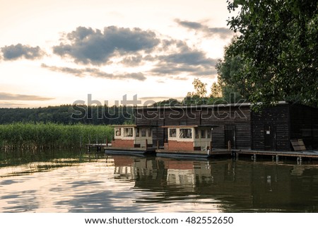 Landscape on a lake with trees and reeds and boatshouse. Royalty-Free Stock Photo #482552650