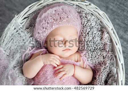 Beautiful little newborn girl 1 month sleeps in a wattled basket. Clousup picture