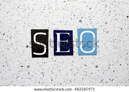 SEO (Search Engine Optimization) acronym cut from newspaper on white handmade paper texture