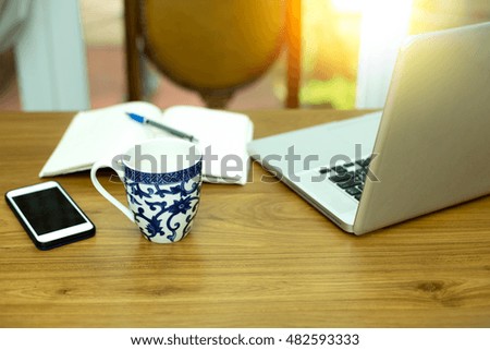 Coffee mug with computer notebook and cell phone with sunlight flare