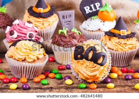 Halloween cupcakes with different decorations made from confectionery mastic, soft focus background