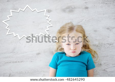 Funny little girl lying on white wooden floor with a speech bubble above her head