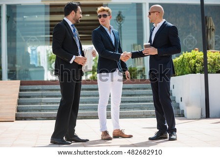 Three young and success arabic businessmen talking outdoor the office, discussing and shaking hands.