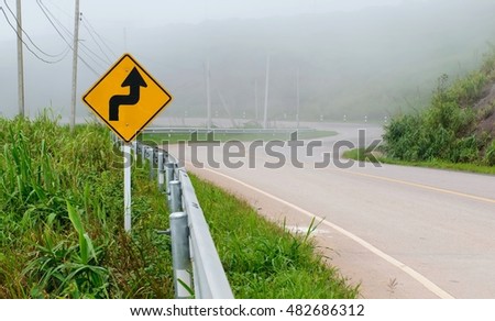 Signs ahead of the curve.Traffic alerts downhill slope. Reduce speed and use a lower gear.arrow traffic sign with blue sky.warning sign on the street.
