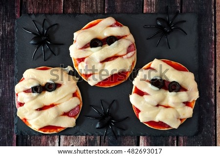 Halloween mummy mini pizzas on slate server with spiders