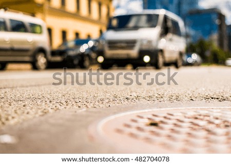 In the downtown, the van passing by on the street. Close up view of a hatch at the level of the asphalt