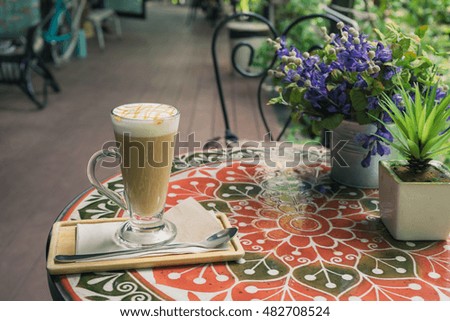 hot fresh coffee in white glass with silver spoon on wooden colorful table lavender flower at sunset at coffee time