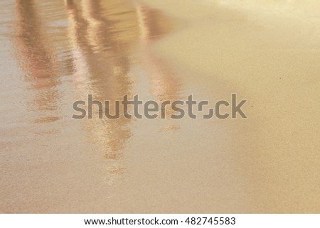 Beautiful sea summer or spring abstract background. Golden sand beach with reflection of people.